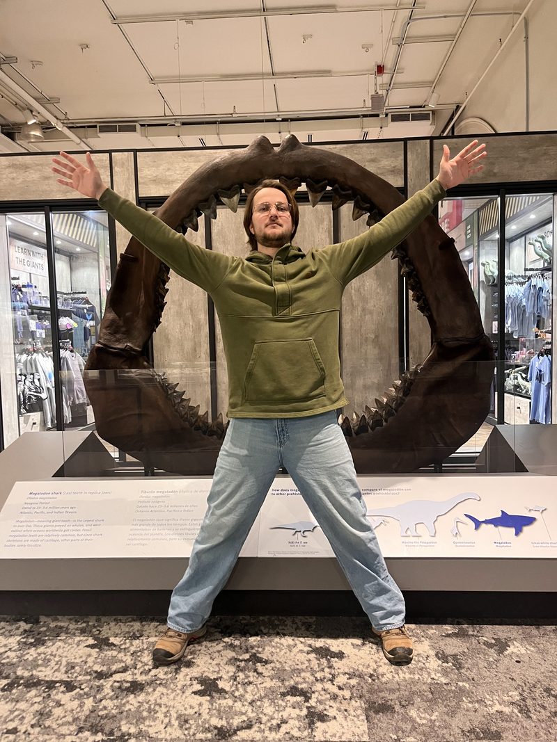 Thor standing arms-out inside a fossil megalodon jaw at a museum
